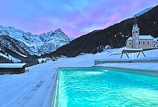 Abendlicher Blick über den Aussenpool im Familienhotel Bella Vista in Südtirol in die Dolomiten. 