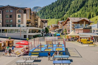 Die Außenansicht des Zauchenseehofs im Salzburger Land zeigt den Hotelbereich mit Spiel- und Aufenthaltsflächen vor der Bergkulisse.