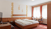 Ein Doppelbett, Schlafcouch und Fernseher im Familienzimmer im Kinderhotel Bruckwirt in Oberösterreich.