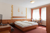 Ein Doppelbett, Schlafcouch und Fernseher im Familienzimmer im Kinderhotel Bruckwirt in Oberösterreich.