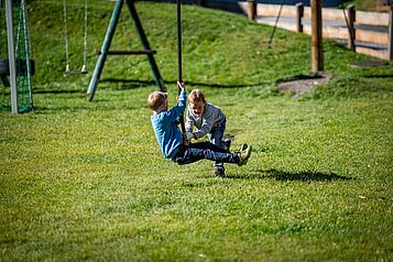 Zwei Jungs spielen auf dem Outdoor Spielplatz des Familienhotels Oberkarteis.