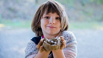 Mädchen spielt mit Naturmaterialien in der Kinderbetreuung im Familienhotel Castellare di Tonda in der Toskana.