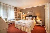 Stilvoll eingerichtetes Gästezimmer im Familienhotel Borchards Rookhus an der Mecklenburgischen Seenplatte mit auffälligen roten und weißen Streifen an den Wänden, gemütlicher Beleuchtung und einladendem Ambiente.