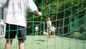 Kinder und Eltern spielen gemeinsam Fußball auf dem Sportplatz des Familienhotel Sonne Bezau.
