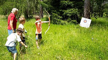 Kinder beim Bogenschießen in der Natur im im Familienhotel Lärchenhof in Tirol 