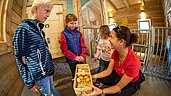 Kinder sammeln Eier im Hühnerstall des Familienhotels Oberkarteis.