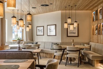 Heller, gemütlicher Restaurantbereich im Zauchenseehof mit warmen Holzelementen, modernem Mobiliar und stilvollen Hängelampen.