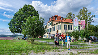 Rhön Ausflugstipp: Familie vor einem Weingut, im Hintergrund sieht man einen See