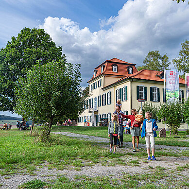 Rhön Ausflugstipp: Familie vor einem Weingut, im Hintergrund sieht man einen See