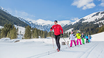 Jugendliche beim Langlaufen im Salzburger Land, gemeinsam mit einem Trainer.