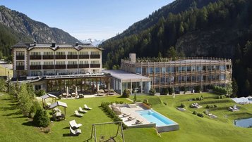 Außenansicht des Familienhotels Bella Vista mit modernem Neubau, Außenpool, Spielplatz und herrlicher Bergkulisse.