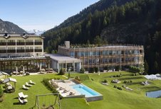 Außenansicht des Familienhotels Bella Vista mit modernem Neubau, Außenpool, Spielplatz und herrlicher Bergkulisse.