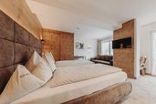 Modernes Doppelzimmer mit großem Bett, Sofa und TV im Familienhotel Habachklause.