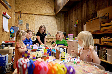 Drei Kinder basteln und werken in der Kreativwerkstatt für Kinder im Familienhotel Habachklause im Salzburger Land.