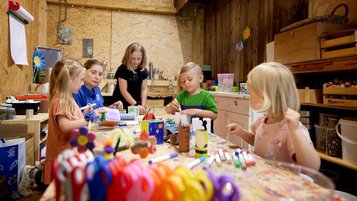 Drei Kinder basteln und werken in der Kreativwerkstatt für Kinder im Familienhotel Habachklause im Salzburger Land.