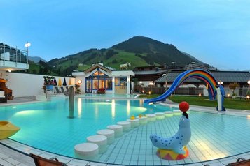 Pool mit Kinderrutsche und anderen Spielmöglichkeiten mit Ausblick auf die Berge im Wellness- & Familienhotel Egger in Saalbach Hinterglemm.