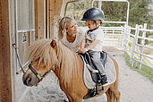 Kleiner Junge sitzt auf einem Pony im Reitstall des Habachklause Familien Bauernhof Resorts im Salzburger Land.