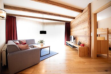 Wohnbereich mit Sofa und TV in einer geräumigen Familiensuite im Familienhotel Sonnenpark.