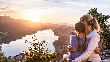 Wandern im Salzburger Land: Mutter und Tochter betrachten den Sonnenuntergang Arm in Arm auf dem Aussichtspunkt Ellmaustein