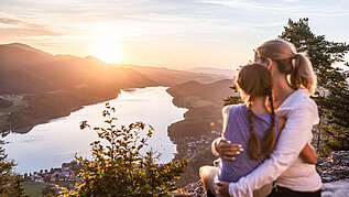 Wandern im Salzburger Land: Mutter und Tochter betrachten den Sonnenuntergang Arm in Arm auf dem Aussichtspunkt Ellmaustein