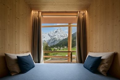 Gemütliche Sitzecke am Fenster im Hotel Bella Vista in Südtirol mit Blick auf die Berge und die Natur.