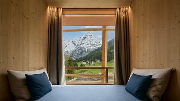 Gemütliche Sitzecke am Fenster im Hotel Bella Vista in Südtirol mit Blick auf die Berge und die Natur.