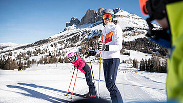 Mitter und Tochter stehen auf Skiern auf einer frisch präparierten Piste.
