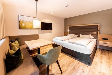 Gemütlicher Elternschlafbereich mit Doppelbett, Sitzecke und modernem Design im Familienhotel Das Bayrischzell