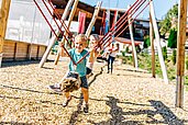 Kinder spielen auf dem Outdoor-Spielplatz des Familienhotels Das Hopfgarten in Tirol.
