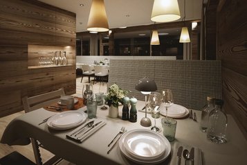 Der Speisesaal Valuna im Familienhotel Gorfion in Liechtenstein mit gedecktem Tisch und Blick in den Restaurantbereich.