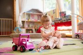 Kleines Kind spielt liebevoll mit einer Puppe in der Babybetreuung im Familienhotel Alpenhotel Kindl.