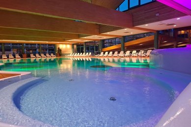 Beleuchteter Indoorpool im Familienhotel Sonnenhügel in der Rhön mit zahlreichen Liegen zum Entspannen.