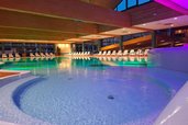 Beleuchteter Indoorpool im Familienhotel Sonnenhügel in der Rhön mit zahlreichen Liegen zum Entspannen.