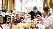 Familie sitzt beim Familienfühstück im gemütlich eingerichteten Restaurant im Familienhotel Sonnenpark im Hochsauerland. 
