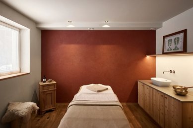 Ein gemütlicher Massageraum im Familienhotel Bella Vista in Südtirol mit Behandlungsliege, warmen Farben und Holzmöbeln.