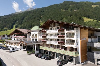 Sommerliche Außenansicht vom Familienhotel Alpenhotel Kindl inmitten der Tiroler Bergwelt.
