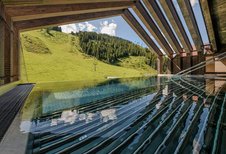 Der Poolbereich des Zauchenseehofs im Salzburger Land bietet einen freien Blick auf die grüne Hanglandschaft.