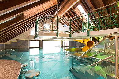 Schwimmbad mit Kinderrutsche und Sitzen im Becken vom Familienhotel Das Kaltschmid in Seefeld in Tirol.