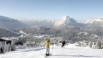 Zwei Skifahrer auf der Piste mit Blick auf das verschneite Seefeld in Tirol