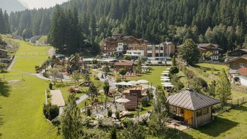 Sommerliche Außenansicht des Familienhotel Habachklause mit großem Garten, Spielplatz und umliegenden Bergen.