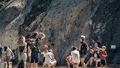 Eine Gruppe Kinder und Teens steht beim Kletterprogramm des Familienhotel Mia Alpina in Tirol vor einer Felswand.