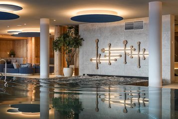 Eleganter Innenpool im Zauchenseehof mit modernen Loungebereichen, dekorativer Wandgestaltung und stimmungsvoller Beleuchtung.