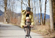 Mutter und Kind mit Helm beim Scooterfahren auf einem Weg nahe dem Familienhotel Das Bayrischzell