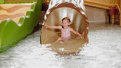 Ein Kind rutscht die Rutsche im Schwimmbad hinunter.