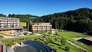 Das Familienhotel Schreinerhof im Bayerischen Wald von außen im Sommer mit einer großen Außenanlage und Outdoor-Spielplatz für Kinder.