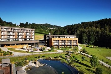 Das Familienhotel Schreinerhof im Bayerischen Wald von außen im Sommer mit einer großen Außenanlage und Outdoor-Spielplatz für Kinder.