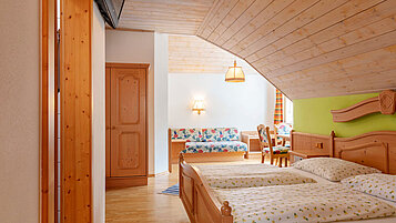 Familienzimmer mit Doppelbett und Sitzbank im Kinderhotel Bruckwirt in Oberösterreich.