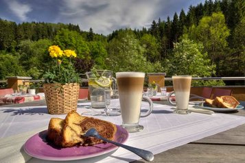 Kaffee und Kuchen auf dem Balkon mit Blick auf die Landschaft im Kinderhotel Bruckwirt in Oberösterreich.