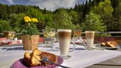 Kaffee und Kuchen auf dem Balkon mit Blick auf die Landschaft im Kinderhotel Bruckwirt in Oberösterreich.