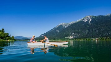 Eine Familie macht eine Bootstour mit einem Paddelboot auf dem idyllischen Weißensee nahe des Familienhotels Ramsi